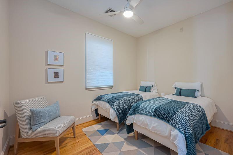 Bedroom with two twin beds in blue patterned bedding and a striped accent chair.