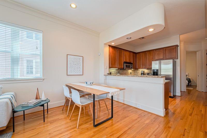 Open kitchen and dining area with dark wood cabinets, stainless steel appliances, and hardwood floors.