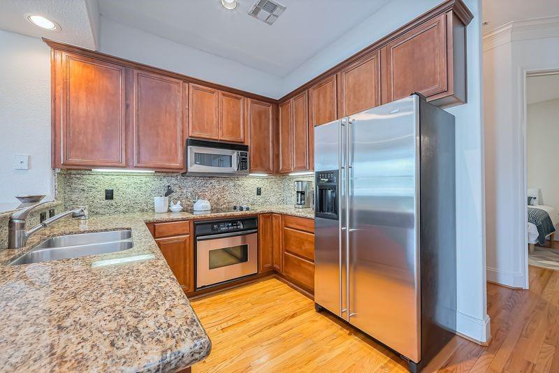 Kitchen with reddish wood cabinetry, granite counters, and stainless steel appliances.
