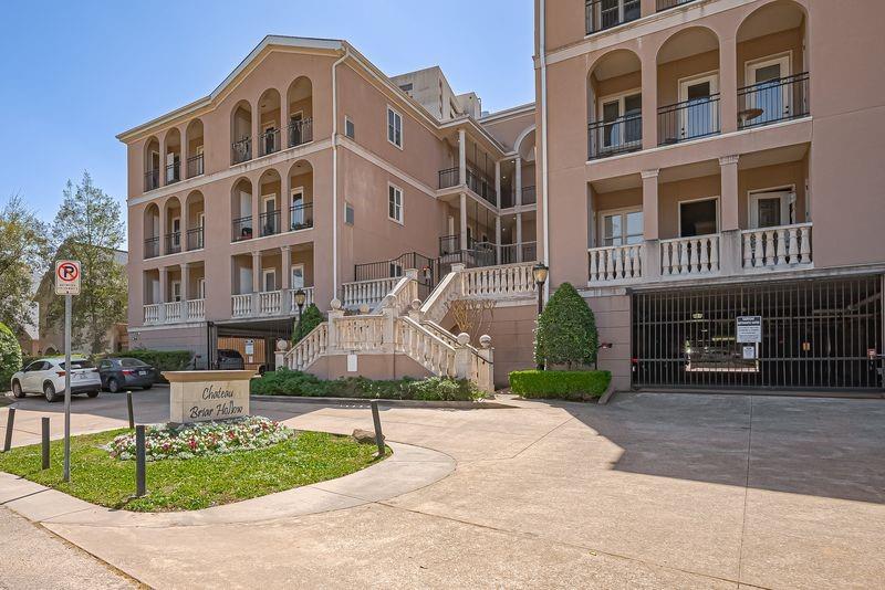 Chateau Briar Hollow exterior with arched balconies, a central staircase, and gated parking.
