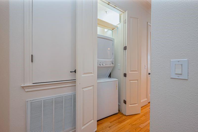 Laundry closet with a stacked washer and dryer behind open paneled doors.