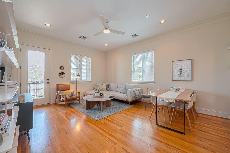Open living and dining area with hardwood floors, gray sectional, and glass balcony door.