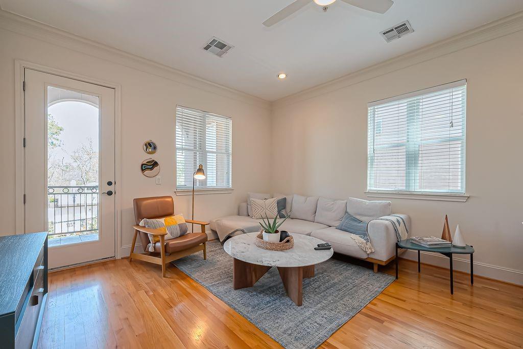 Staged living room with a light sectional, leather armchair, and balcony door.