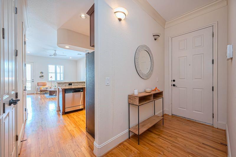 Condo foyer with console table and oval mirror, opening to the kitchen and living area.