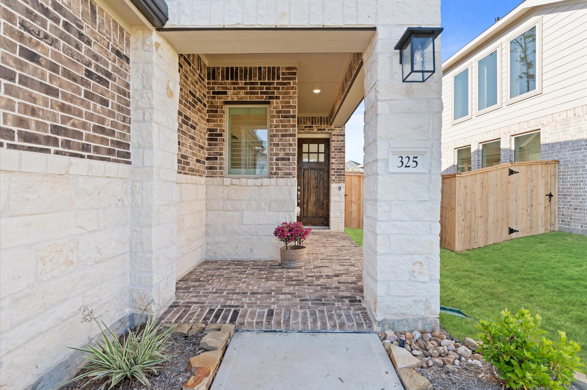 Covered brick-and-stone entry with a dark wood door and a paver walkway.