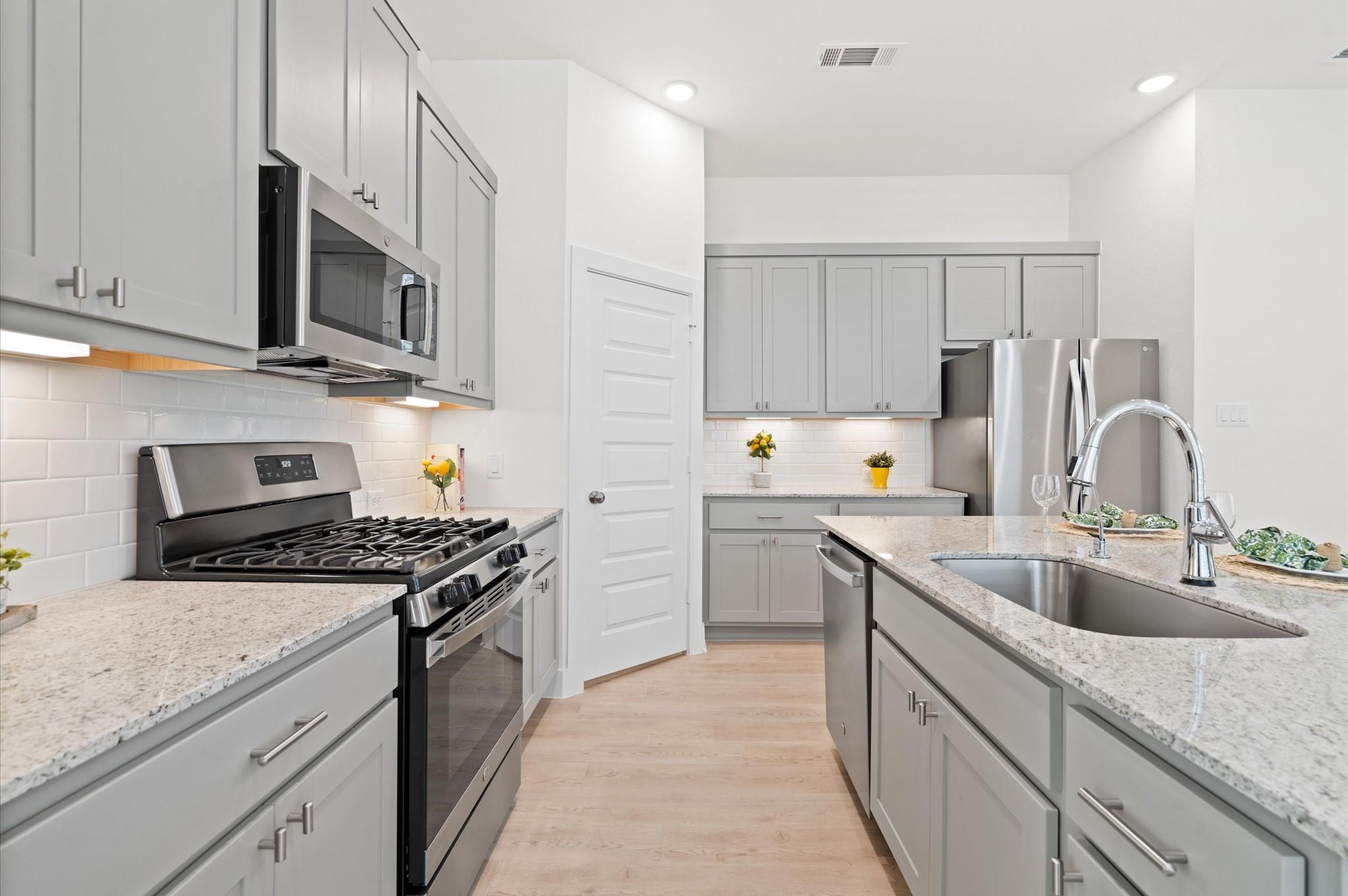 Modern kitchen with gray cabinets, a gas range, and a large island with a double-basin sink.