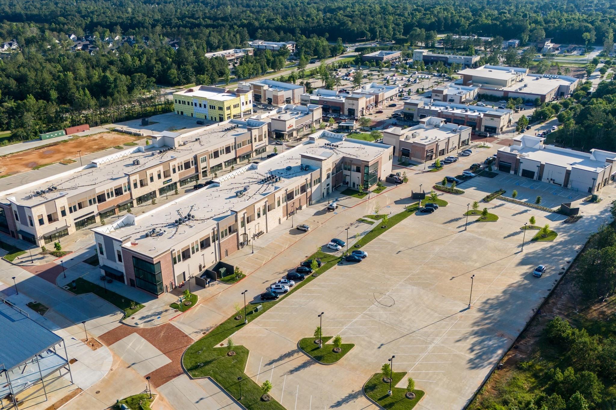 Aerial view of a retail complex with low-rise buildings and expansive parking lots.