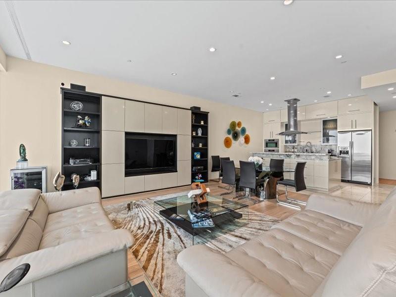Open-plan living room with cream leather sofas, built-in media wall, dining area, and modern kitchen.