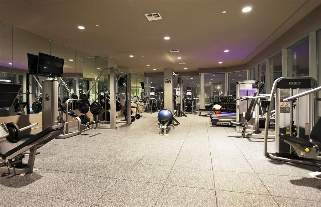 Fitness center with mirrored walls, exercise machines, weight racks, and a blue stability ball.
