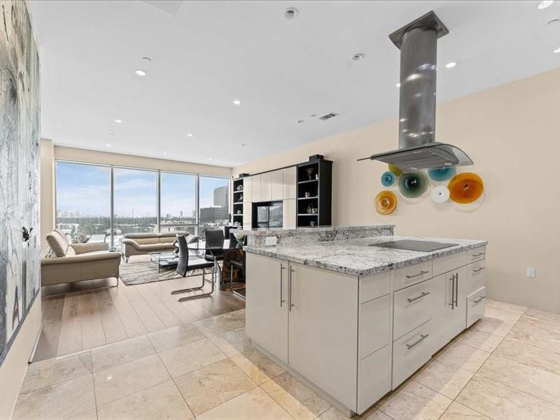 Open-plan condo kitchen with a stone island and floor-to-ceiling windows overlooking the city.