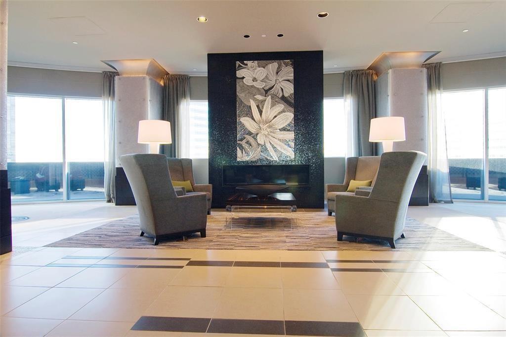 Furnished living room with a central fireplace, floral artwork, and floor-to-ceiling windows.