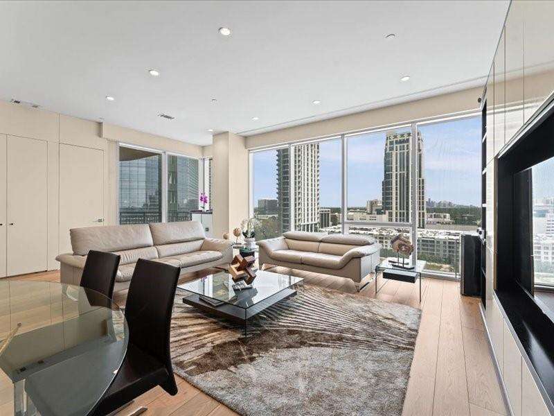 Furnished condo living room with floor-to-ceiling windows overlooking Houston buildings.