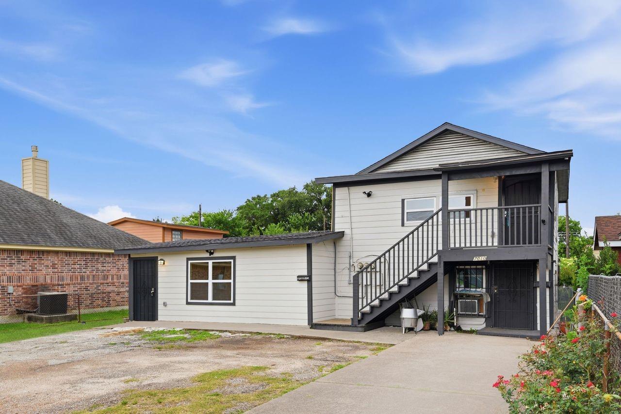 Home with an exterior staircase, covered upper porch, and attached single-story wing.