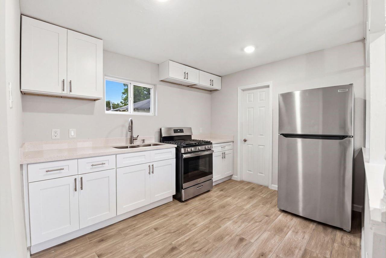 Kitchen with white cabinets, stainless steel appliances, and wood-look tile flooring.