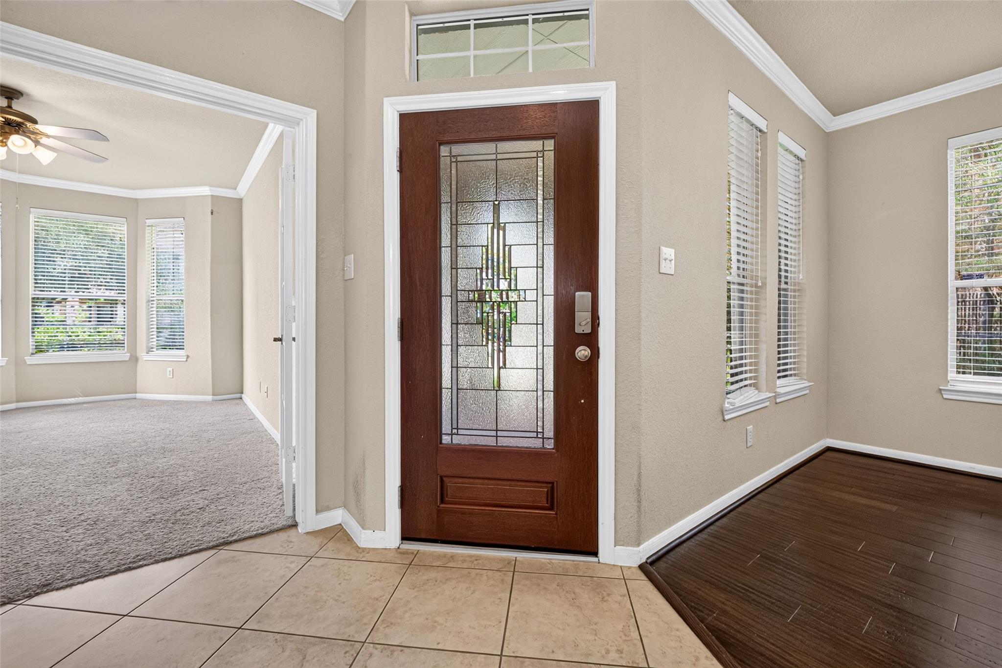 Entryway with a decorative glass front door, tiled floor, and adjoining carpeted room.