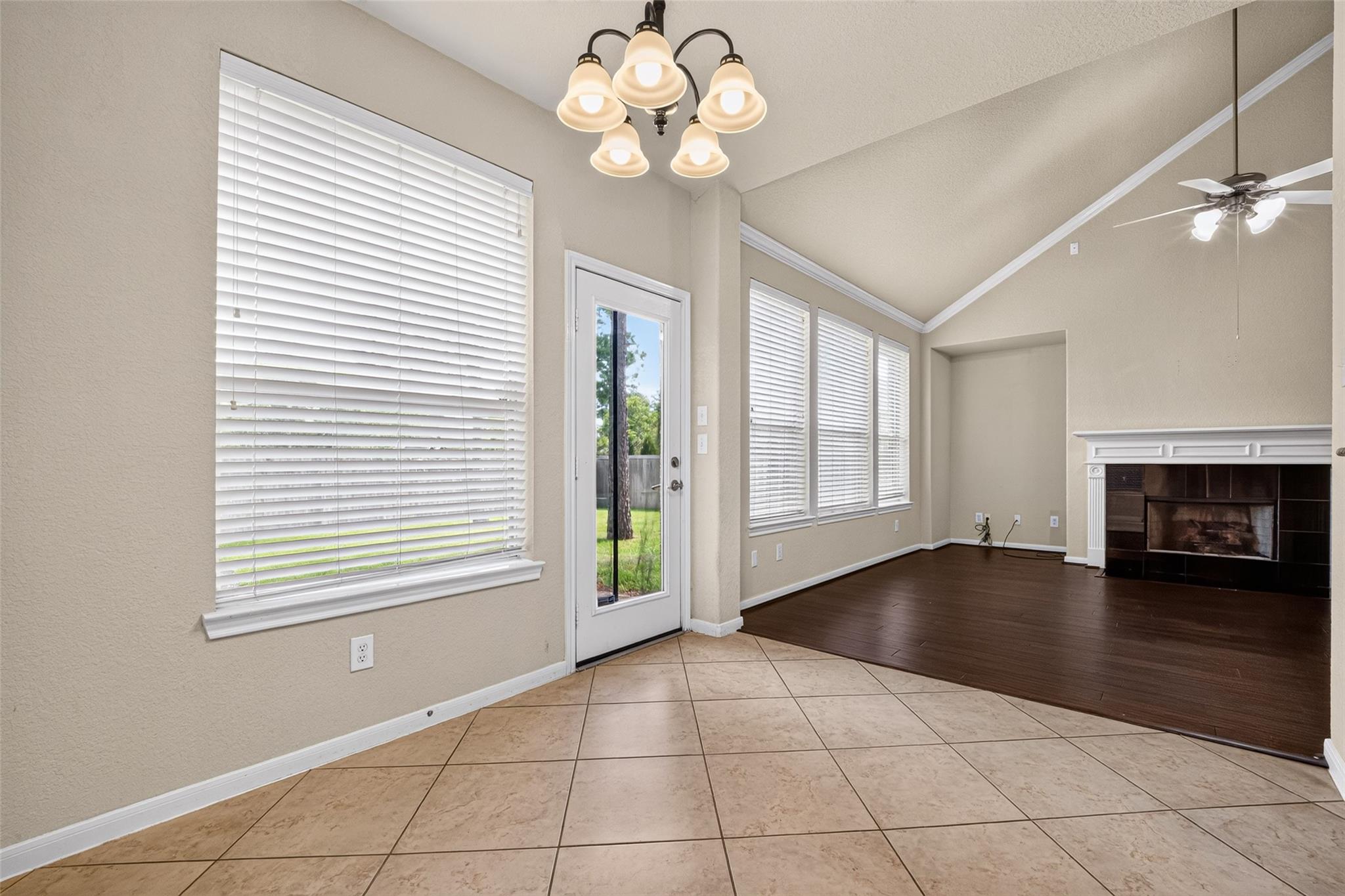 Unfurnished living area with a white fireplace, dark wood flooring, and windows beside a glass patio door.