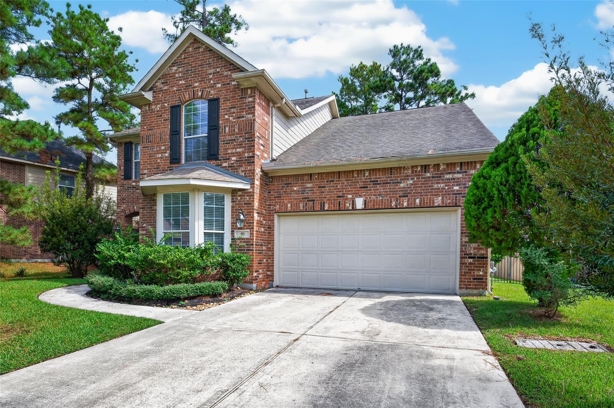 Two-story red-brick home with an attached double garage and landscaped front yard.