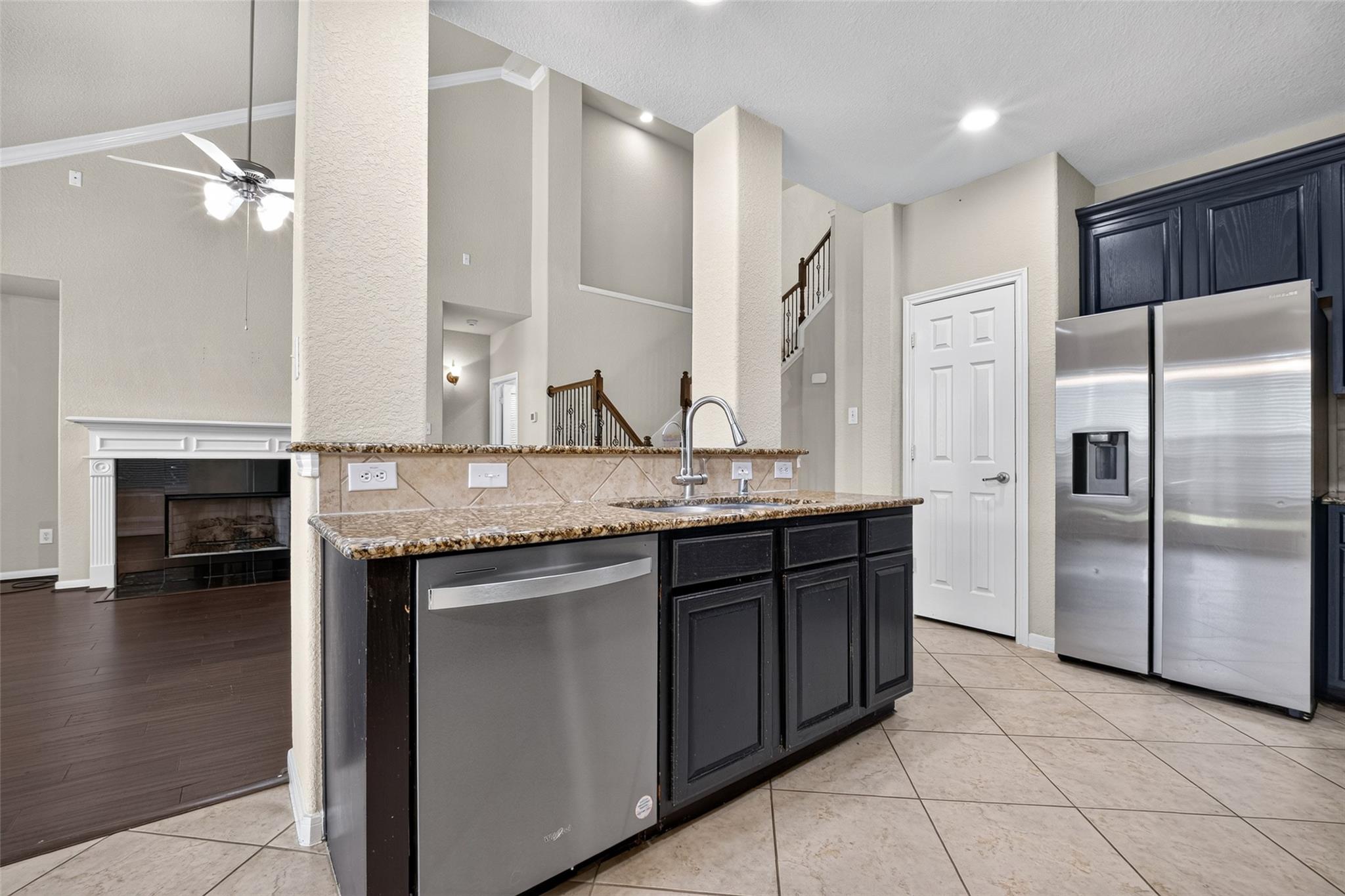 Kitchen with dark cabinets, granite breakfast bar, stainless steel appliances, and an adjacent fireplace.