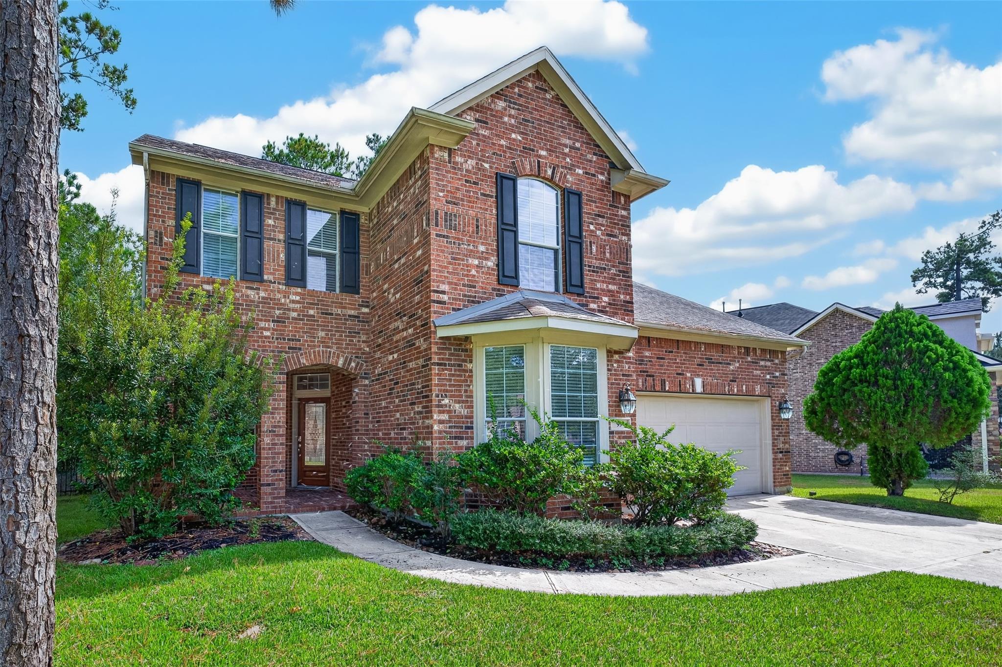 Two-story brick house with dark shutters, a bay window, and an attached garage.