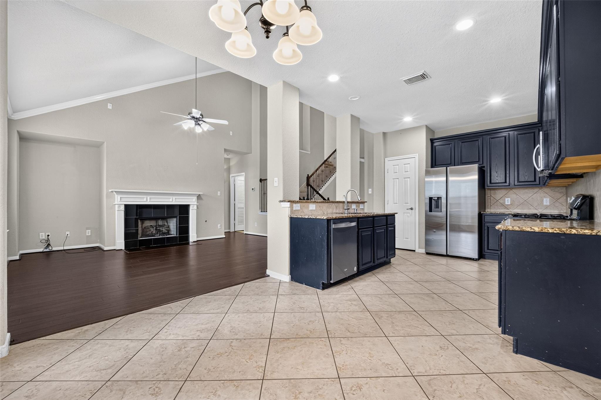 Open kitchen and living area with dark cabinets, stainless appliances, and a fireplace.