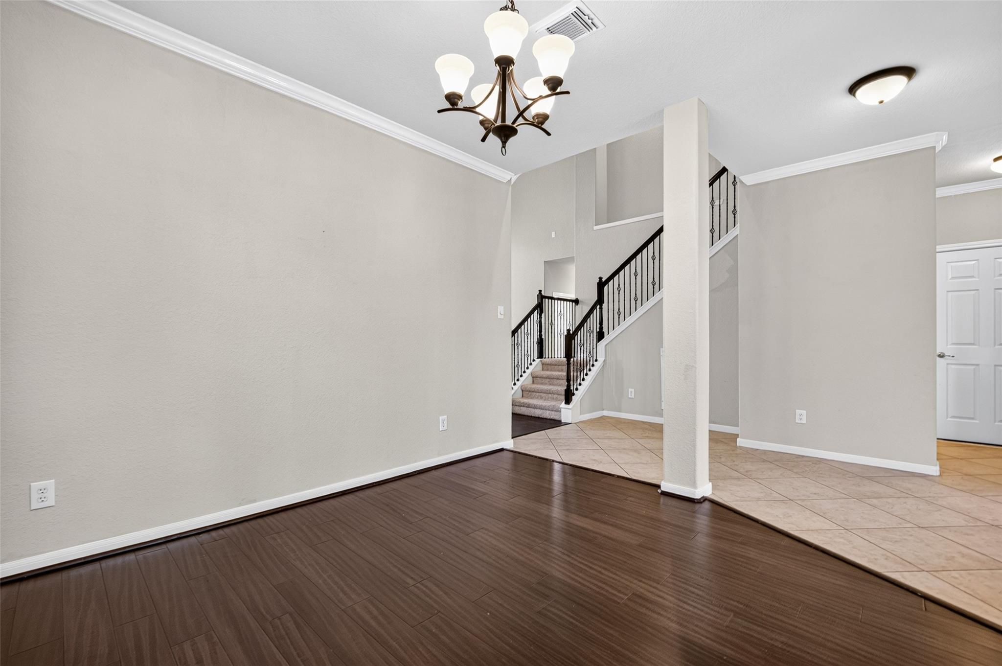 Entry foyer with dark wood flooring, tiled transition, and staircase with black iron railings.