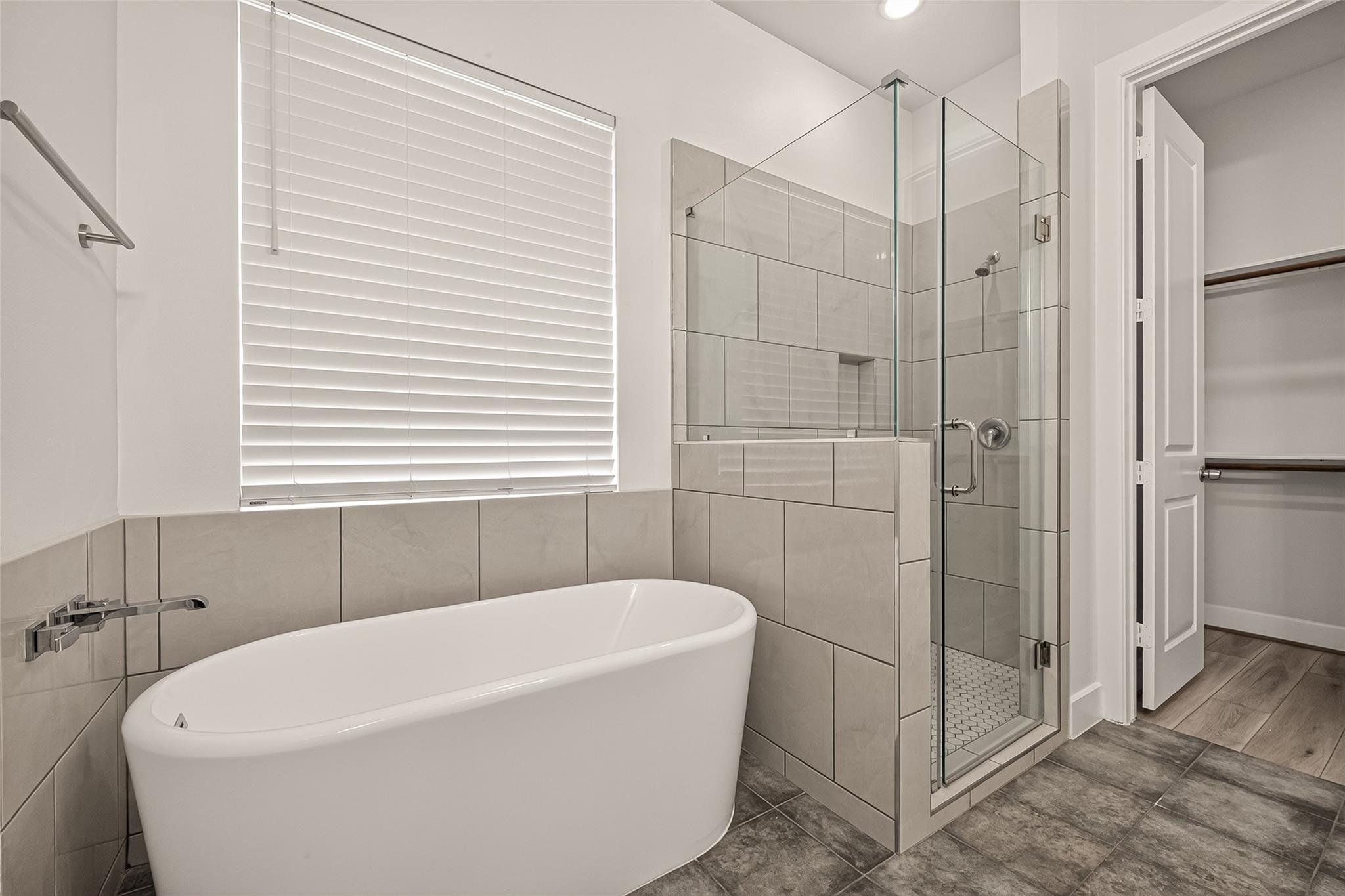 Bathroom with a freestanding tub, glass shower, and an open closet door.