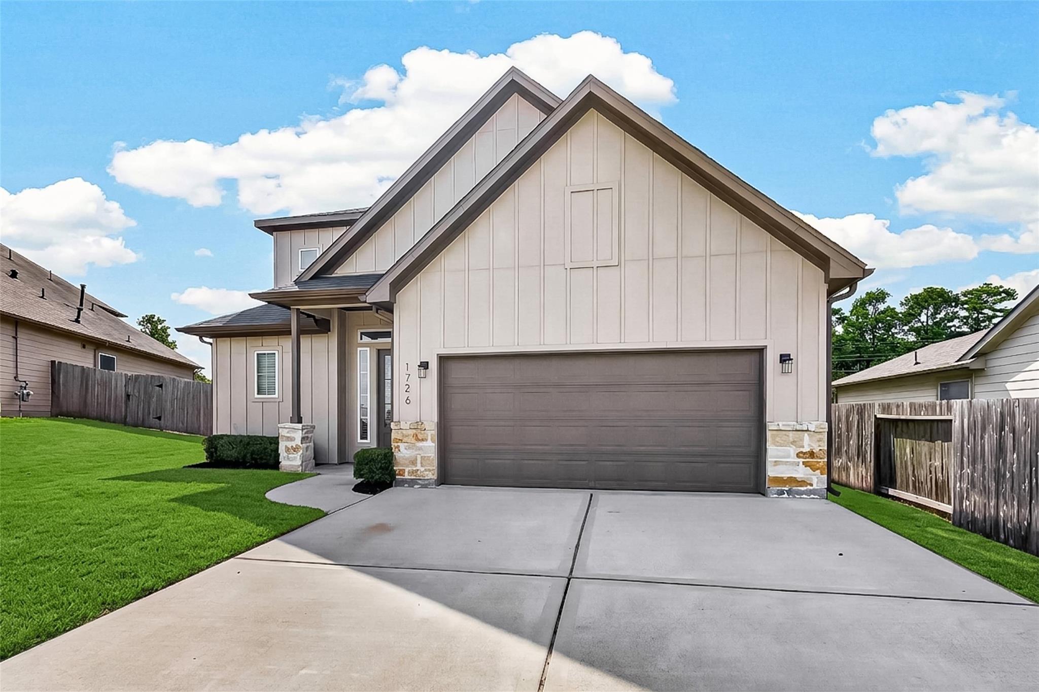 Modern home exterior with steep gables, a two-car garage, stone accents, and a broad concrete driveway.
