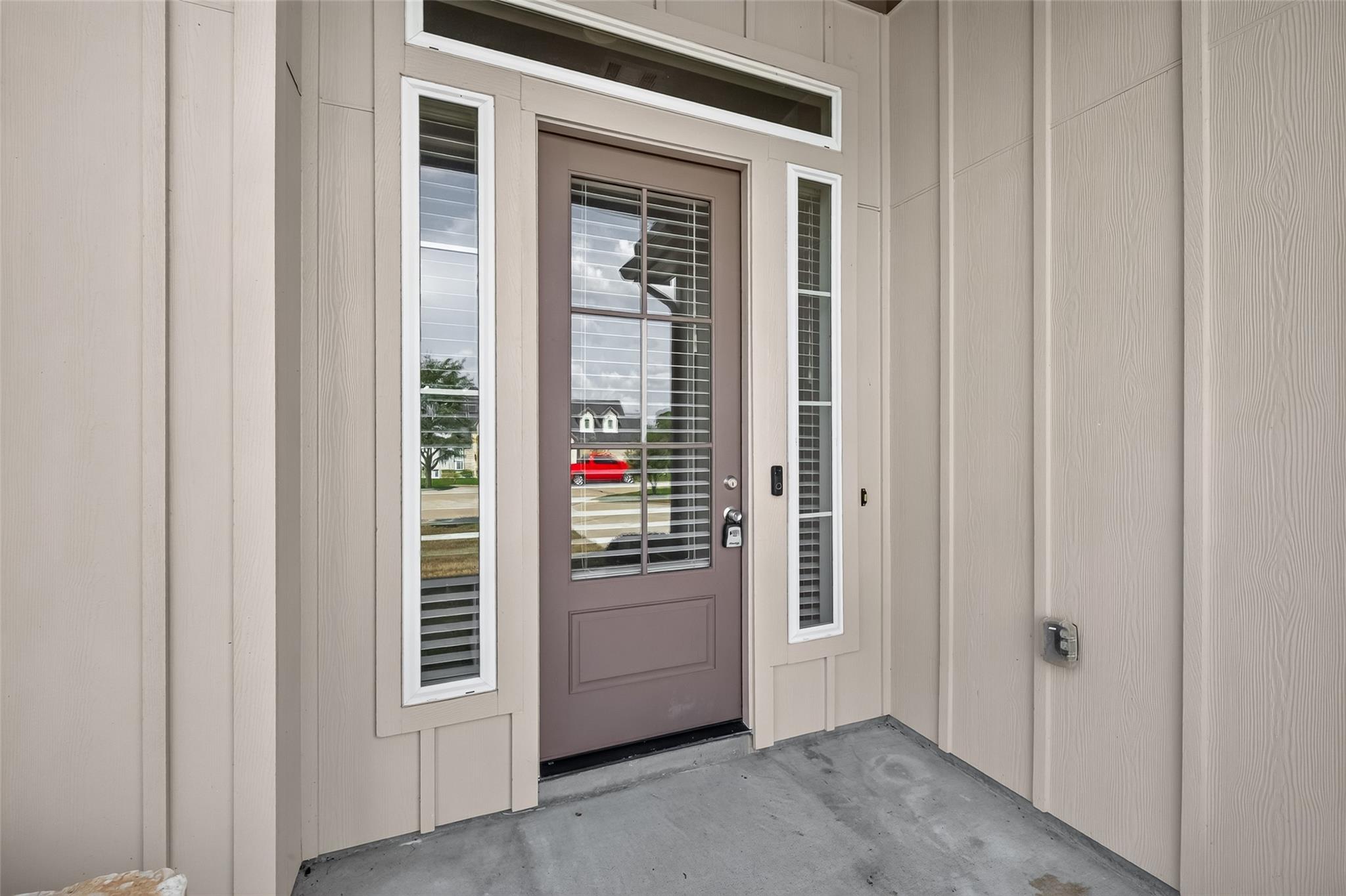 Taupe front door with glass panels and sidelights on a covered porch.