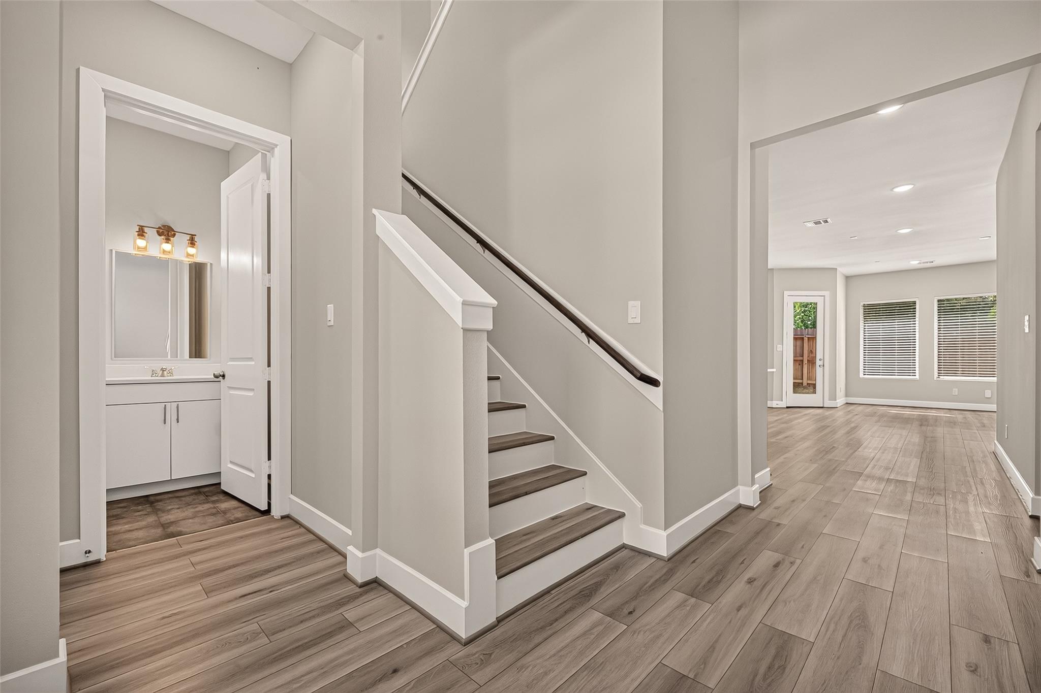 Entry hall with a staircase, powder room vanity, and adjoining living area.