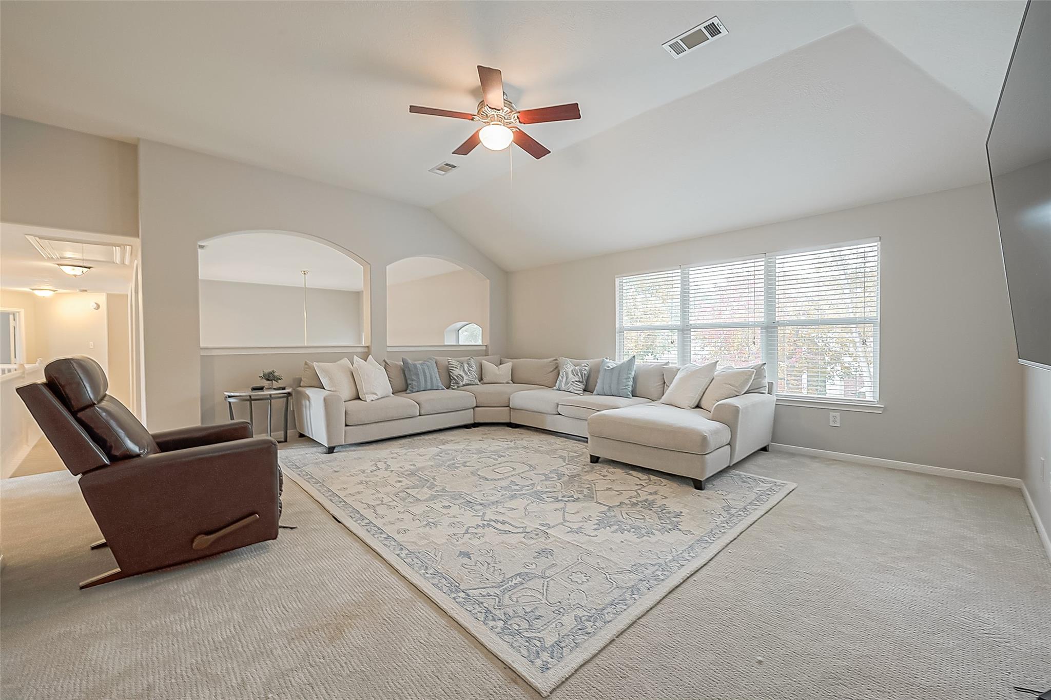Furnished living room with a vaulted ceiling, arched openings, and a large sectional by the windows.