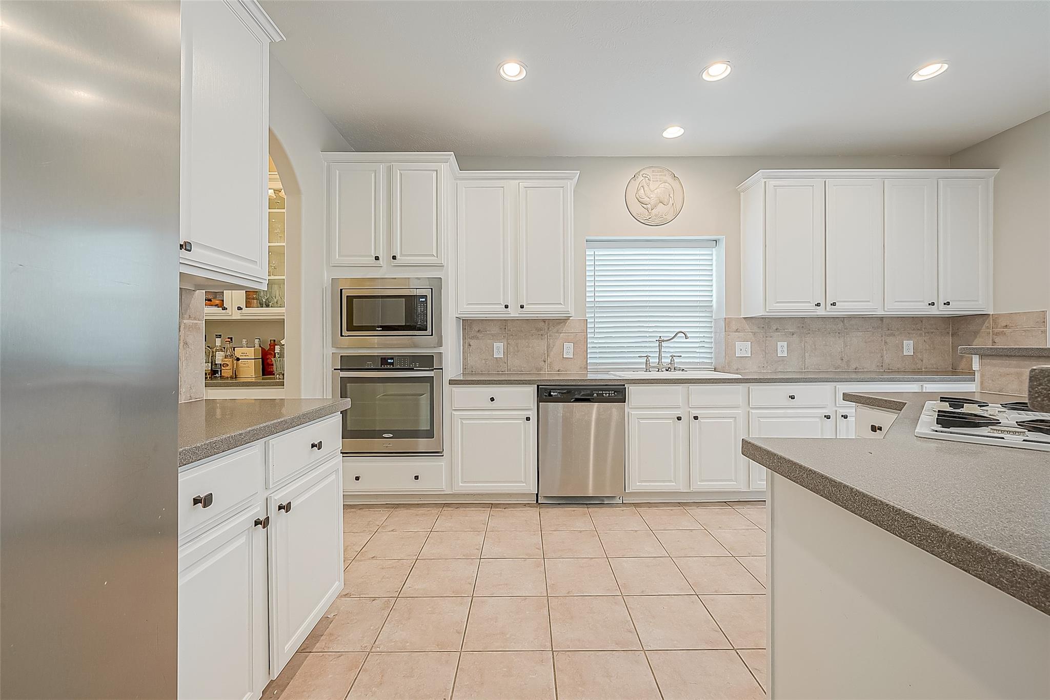 Kitchen with white cabinets, granite counters, stainless steel appliances, and a window above the sink.