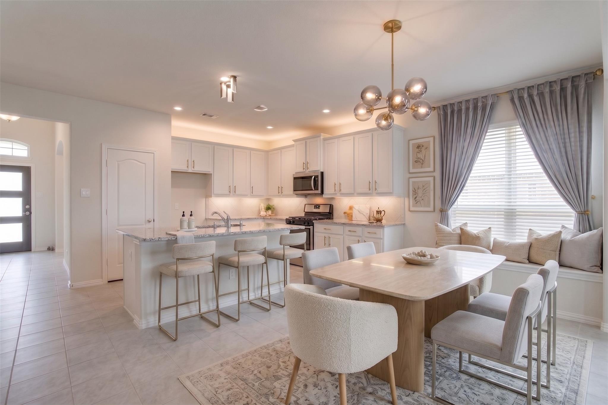 Open-plan kitchen and dining area with white cabinets, a bar peninsula, and a window seat.