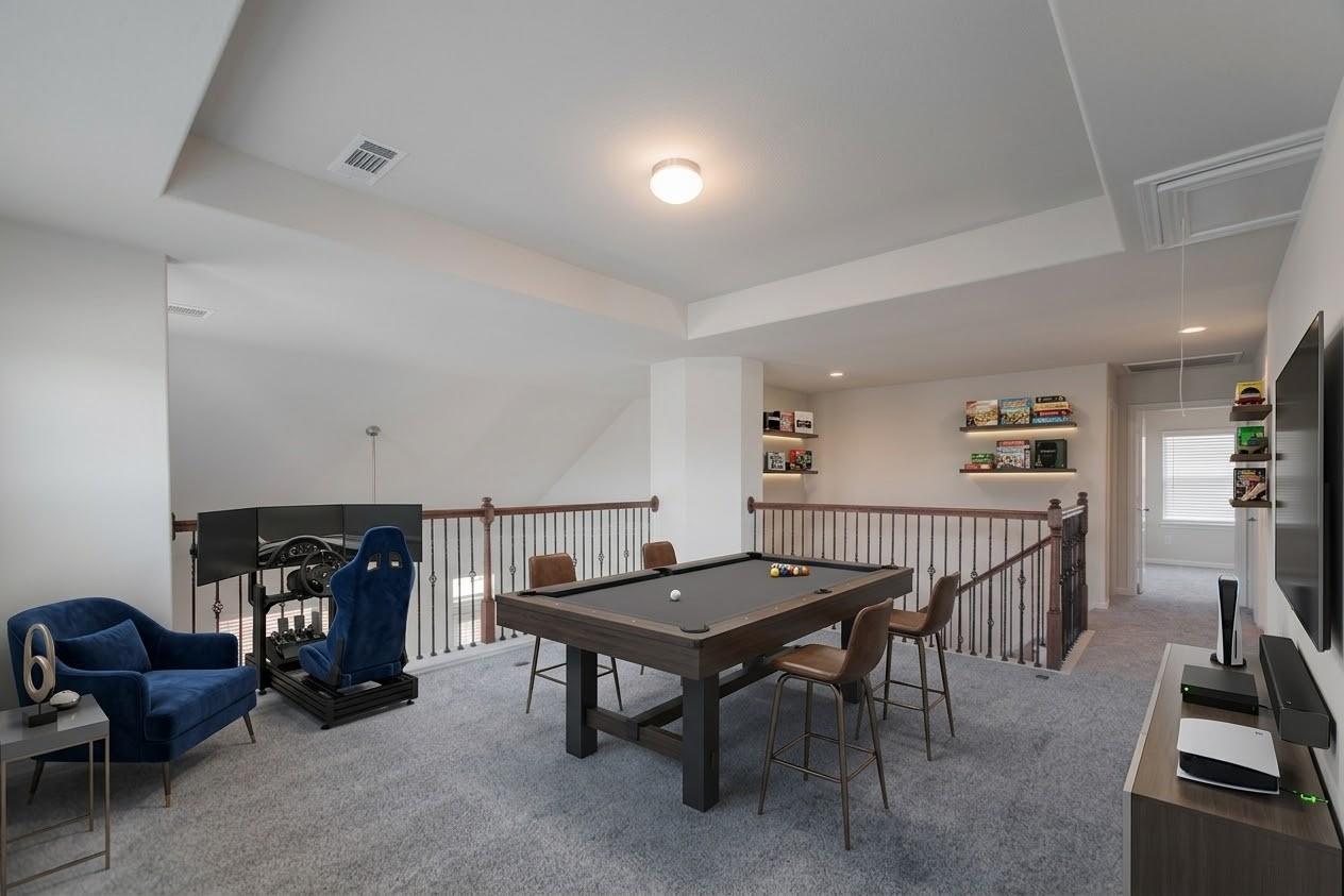Upstairs game room with a pool table, racing simulator, and blue lounge seating.