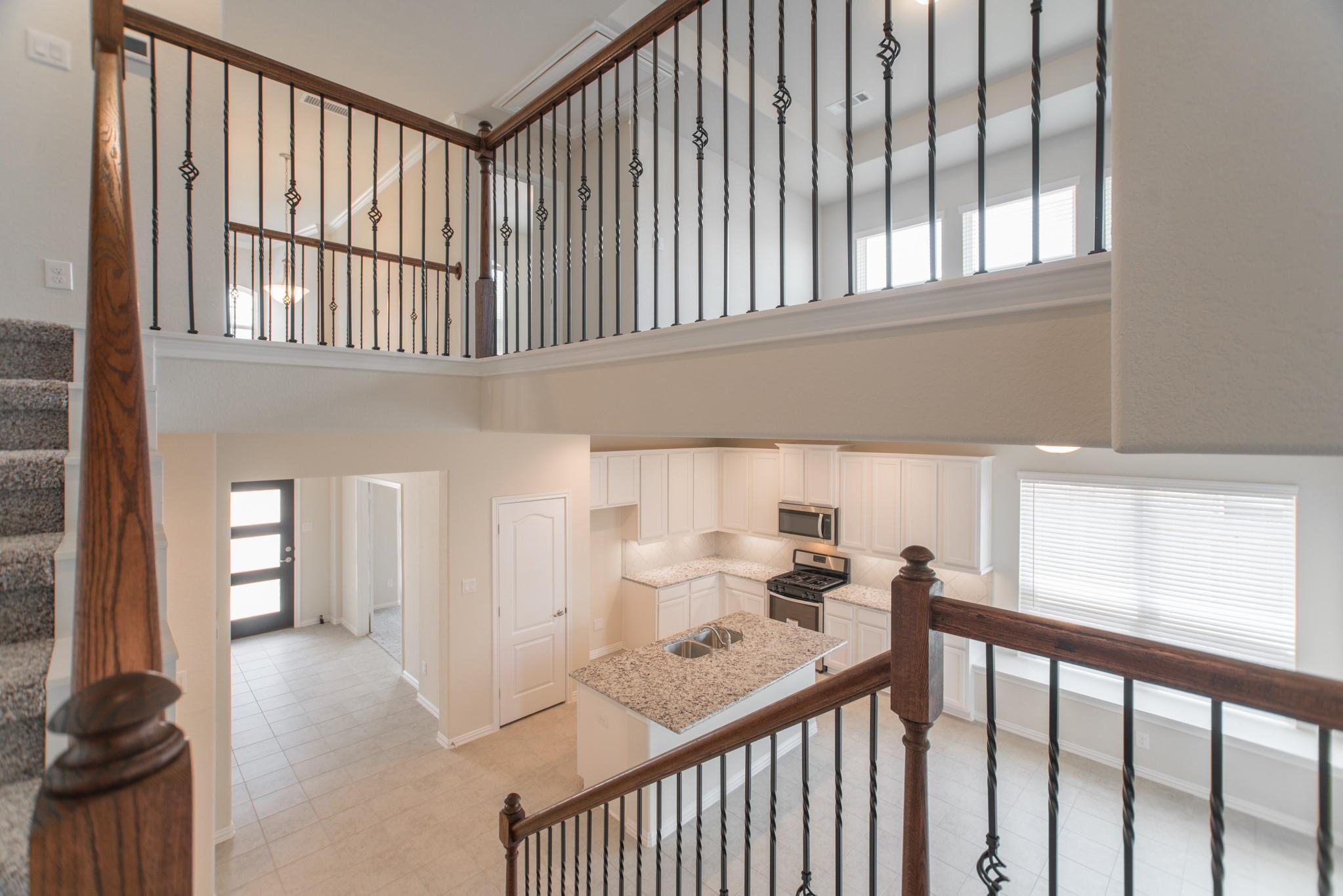 Kitchen with a granite island and white cabinets viewed from the upstairs landing.