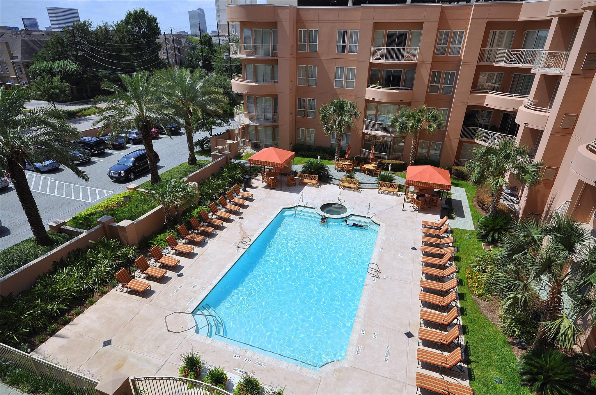 Condominium courtyard pool with an attached spa, palm trees, and rows of lounge chairs.