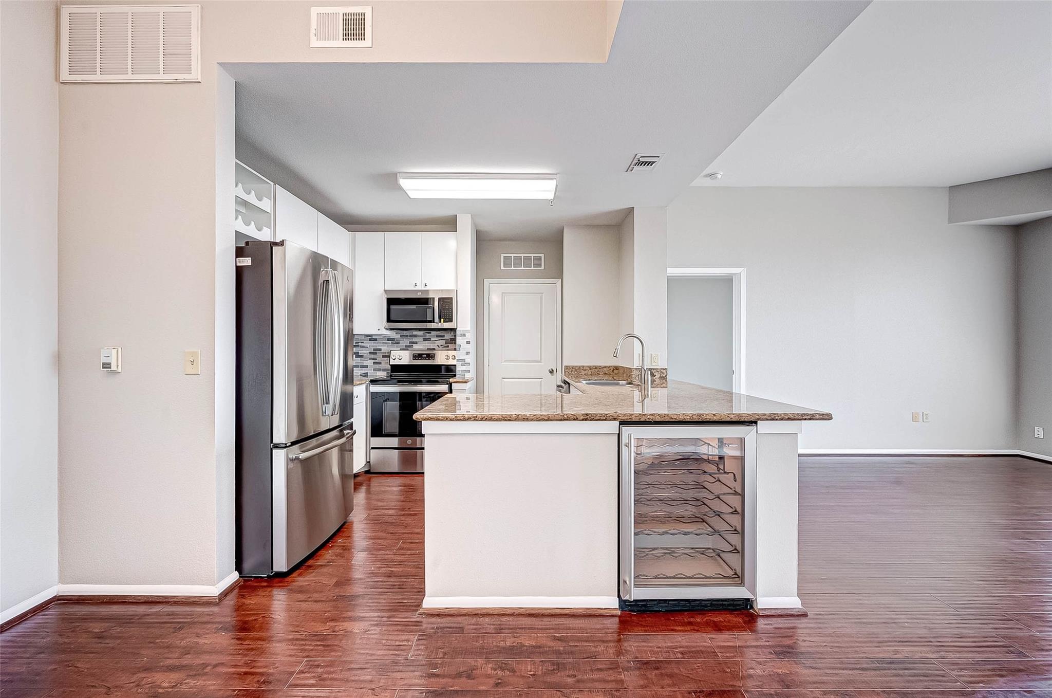 Condo kitchen with stainless steel appliances, a stone-topped island, and built-in wine cooler.
