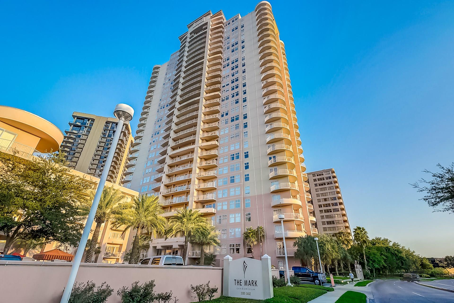 The Mark condominium tower with curved balconies, palm trees, and its 3505 Sage entrance sign.