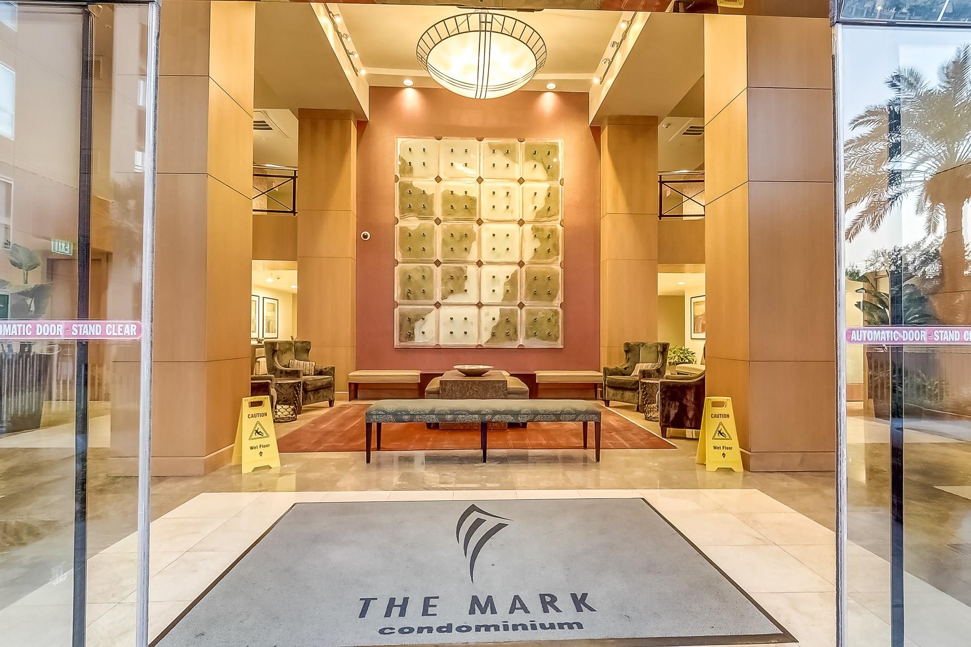 The Mark Condominium lobby with wood-paneled columns, lounge seating, and a large circular ceiling light.