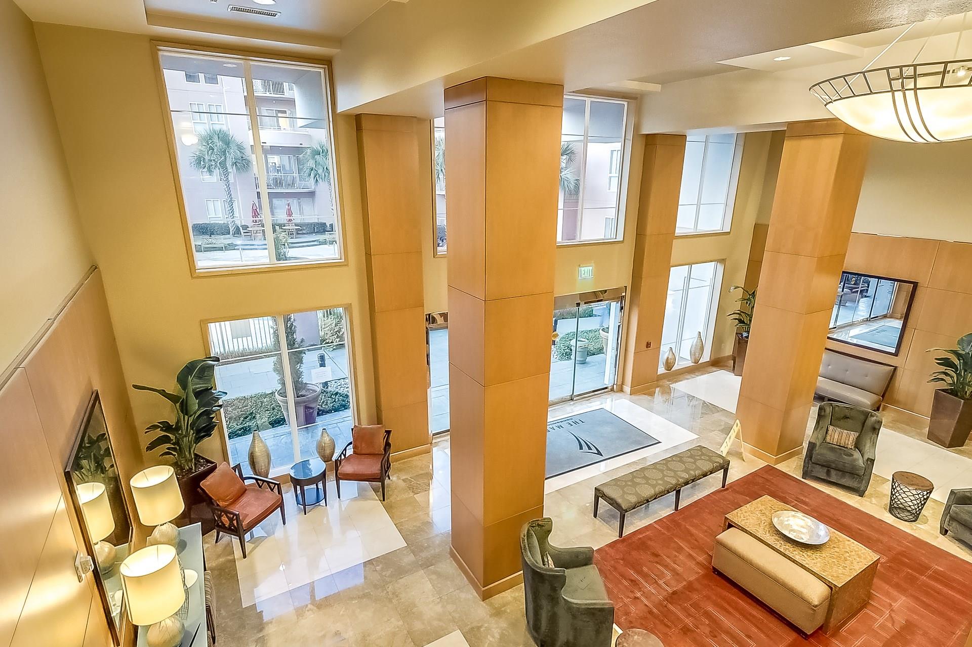 High-rise lobby with wood-paneled columns, tall windows, and furnished seating areas.