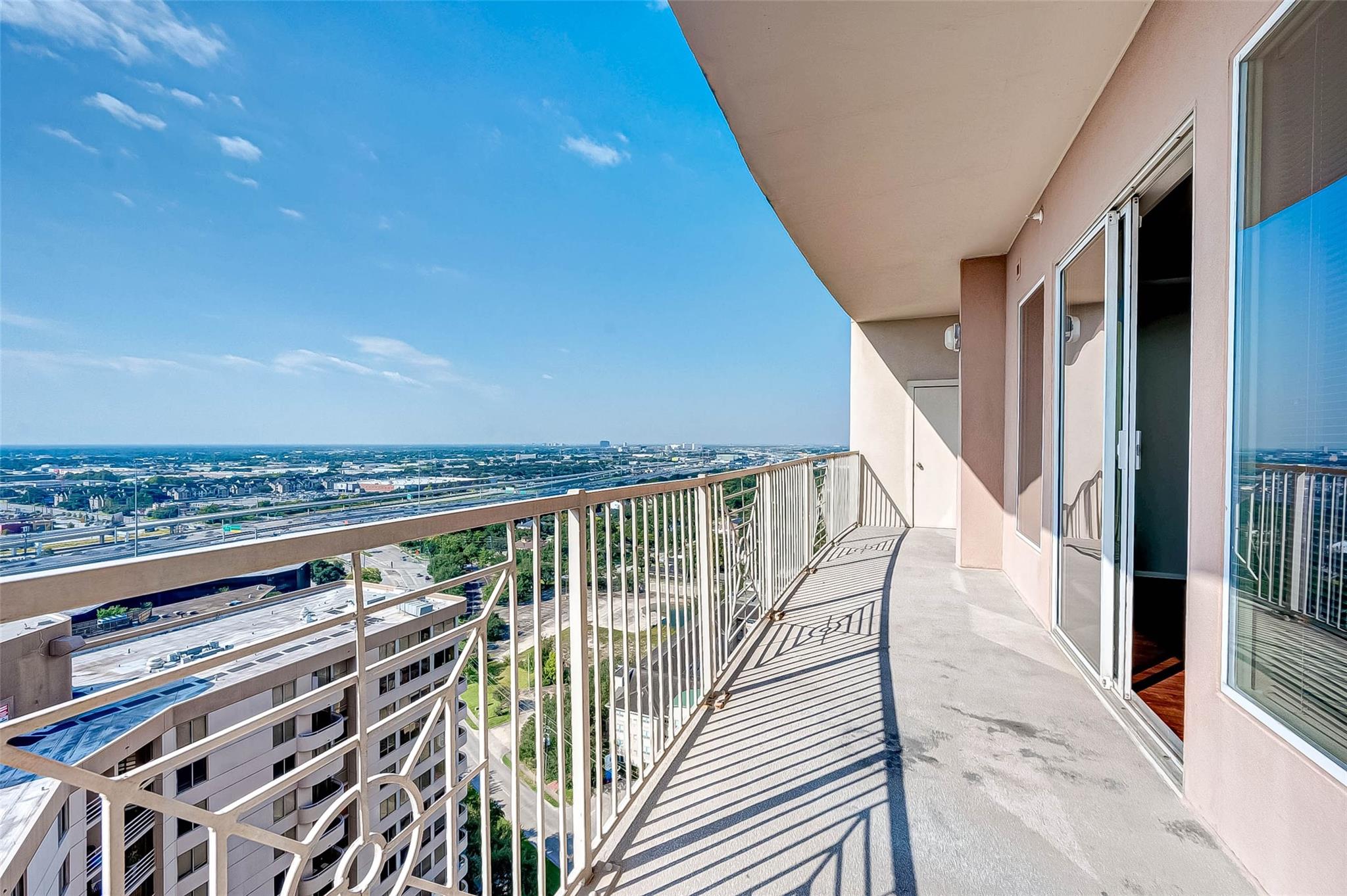 High-rise balcony overlooking Houston, with metal railings and sliding glass doors.