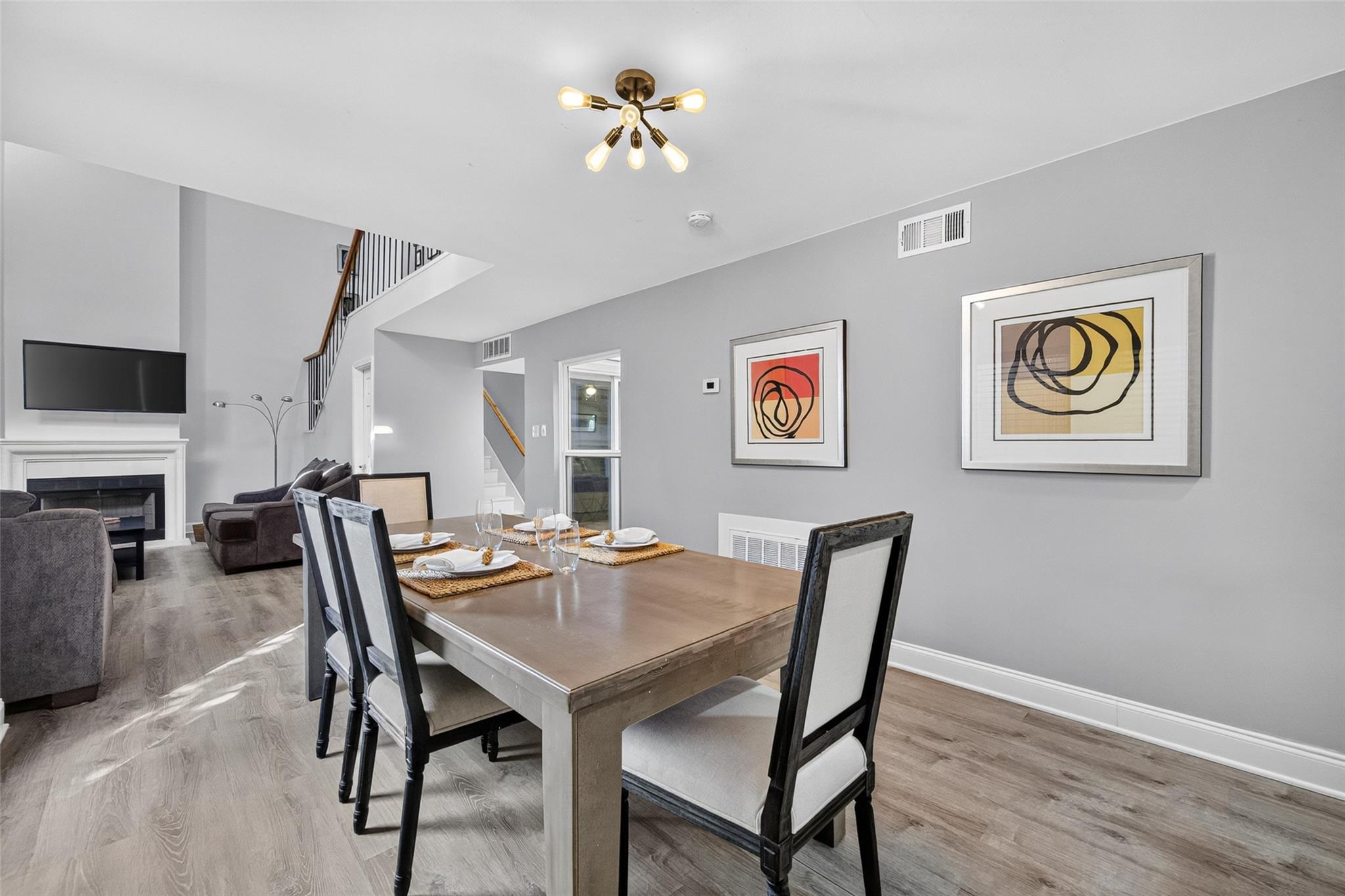 Staged dining area with a wood table opening into a living room and staircase.