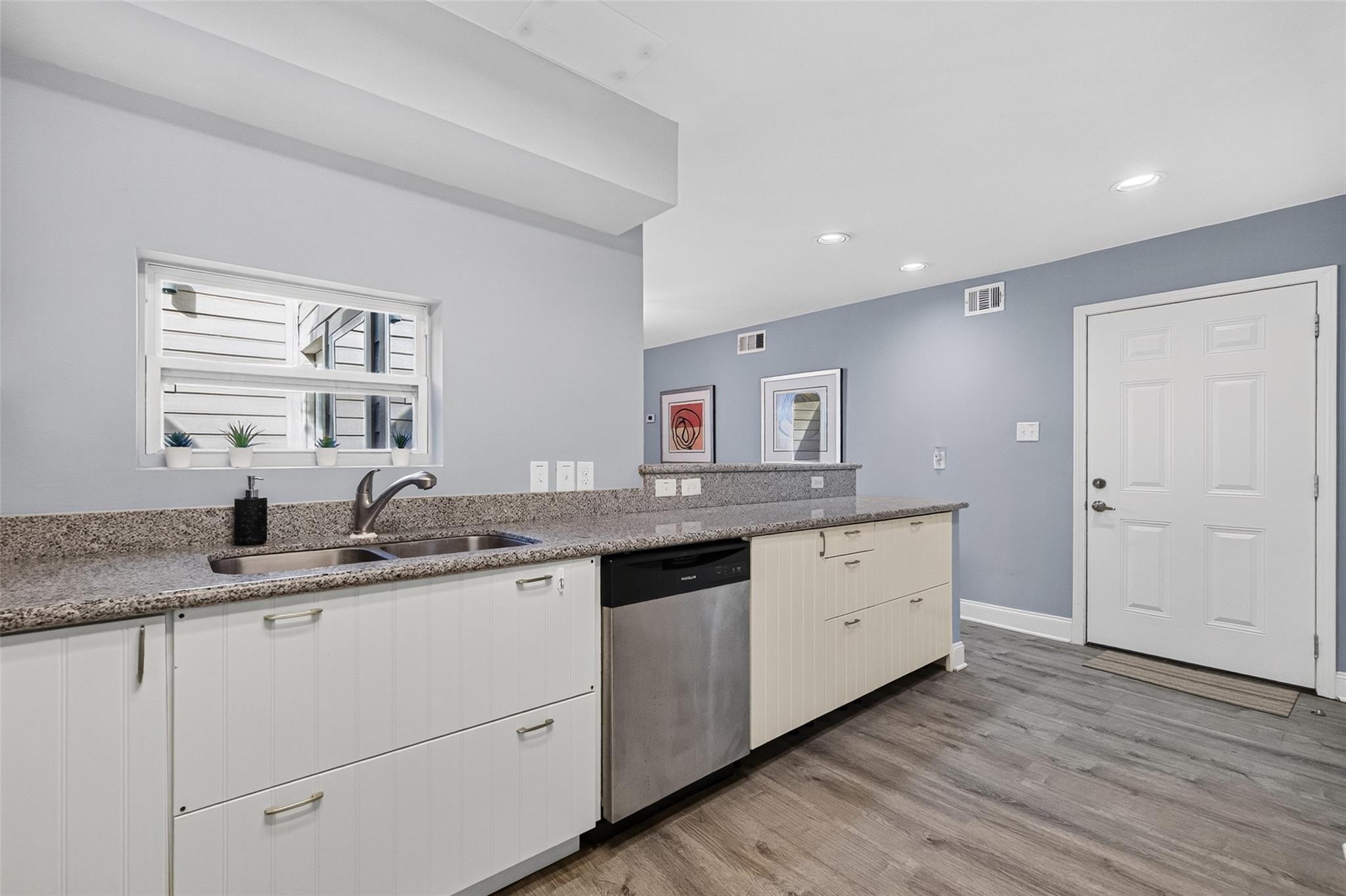 Kitchen with white cabinets, granite counters, a double-basin sink, and stainless-steel dishwasher.