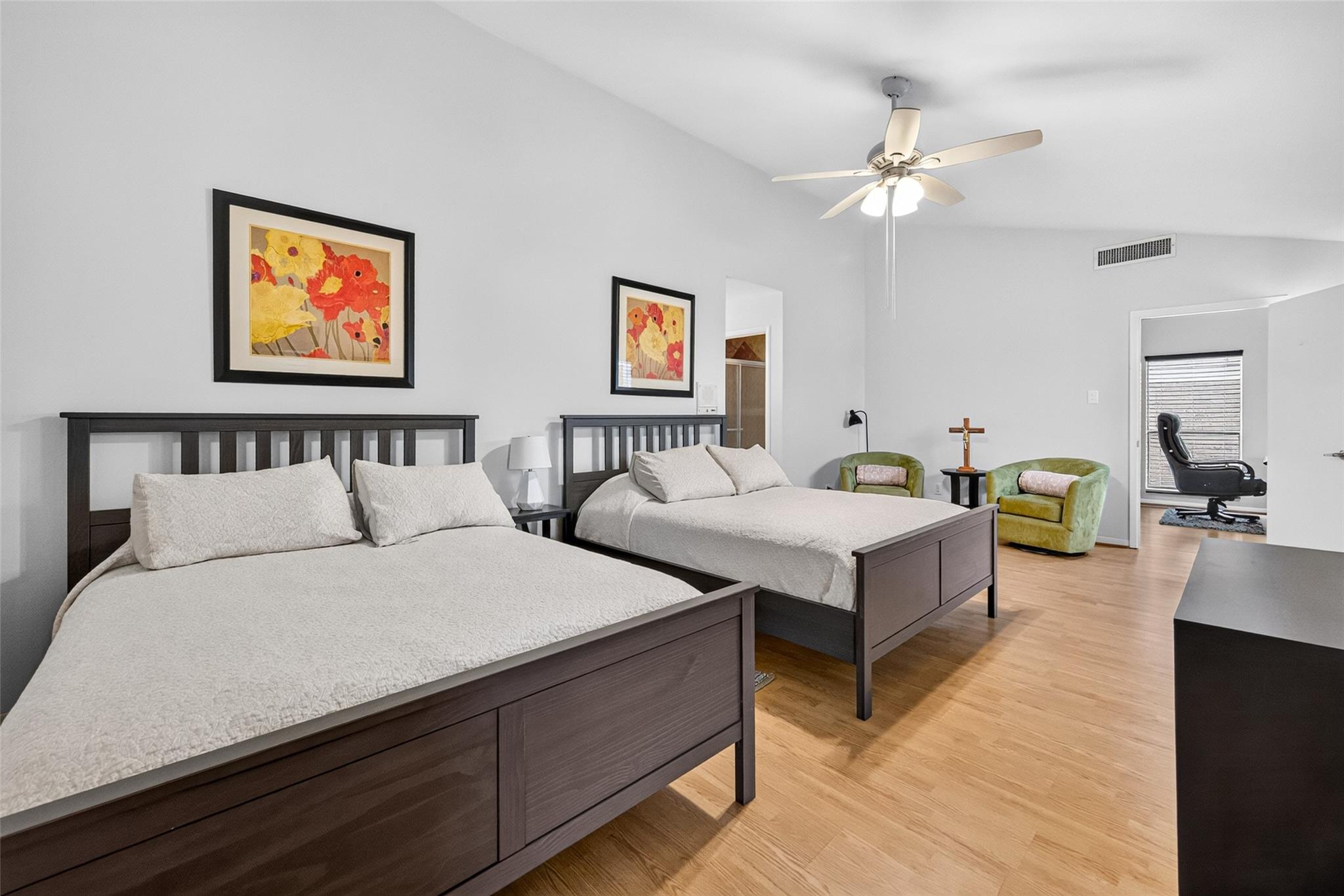 Bedroom with two dark wood beds, white bedding, wood floors, and green armchairs.