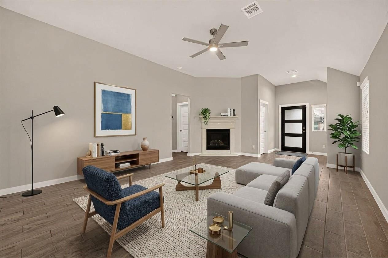 Staged living room with a fireplace, high ceiling, gray sectional, and blue accent chair.