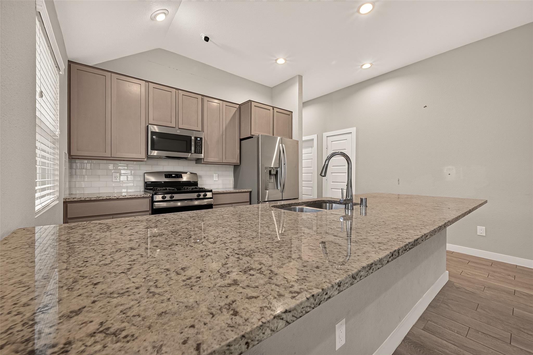 Kitchen with stainless steel appliances and a large granite island with an undermount sink.