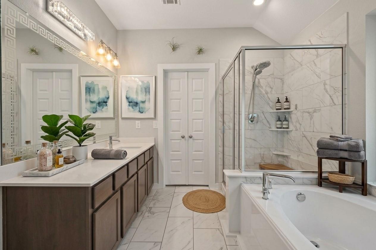 Bathroom with a dark-wood vanity, glass-enclosed marble-look shower, and white soaking tub.