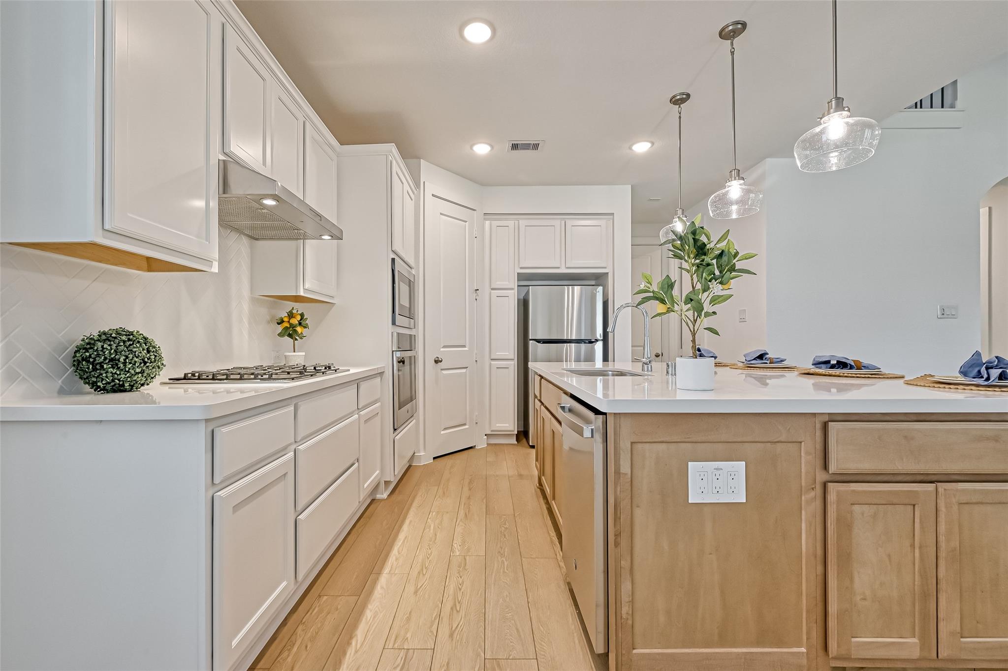 Bright kitchen with white cabinets, stainless steel appliances, and a large wood island.