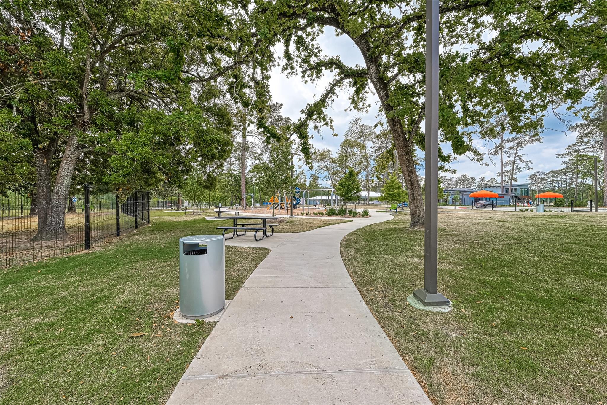 Neighborhood park with a winding walkway, mature trees, picnic tables, and playground.