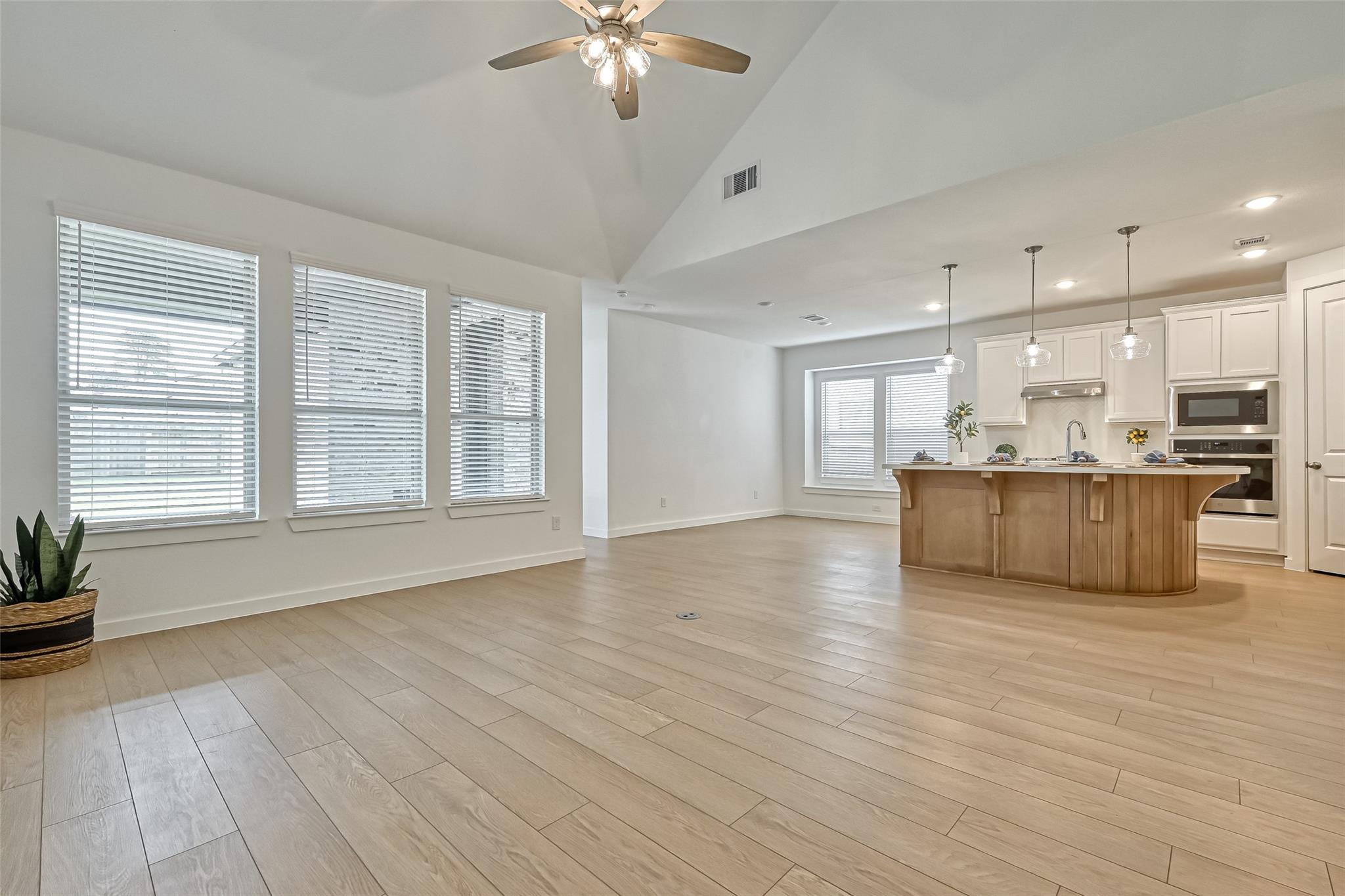 Open-plan kitchen with a large island, vaulted ceiling, and light wood-look tile floors.