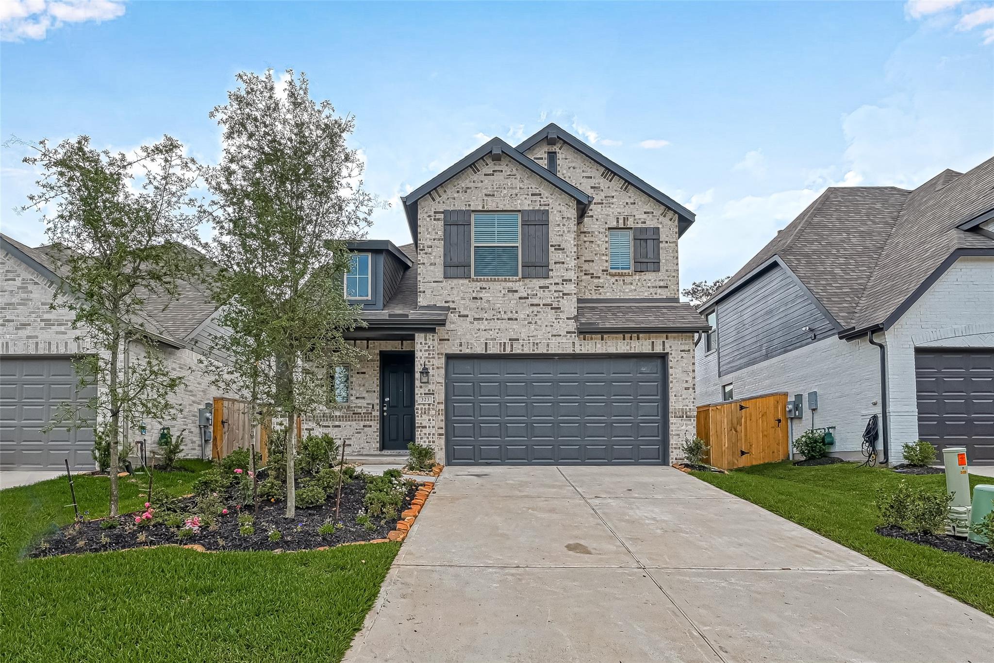 Two-story brick house with dark shutters, a double garage, and landscaped front yard.